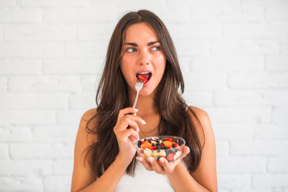 Young Woman Eating Fruit Salad With Fork