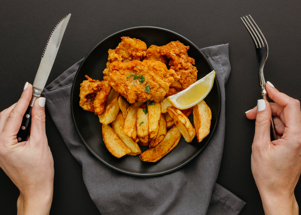 top-view-fish-chips-plate-with-woman-holding-cutlery