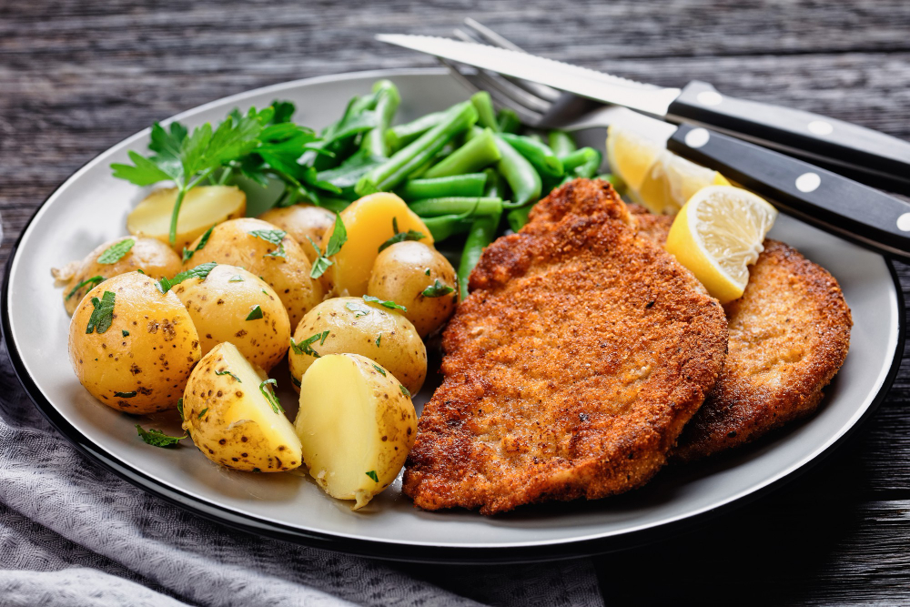 German Pork Schnitzel With Young Potatoes Green Beans With Cutlery Served Plate With Lemon Wedges Mayonnaise Based Sauce Dark Wooden Surface Top View Close Up