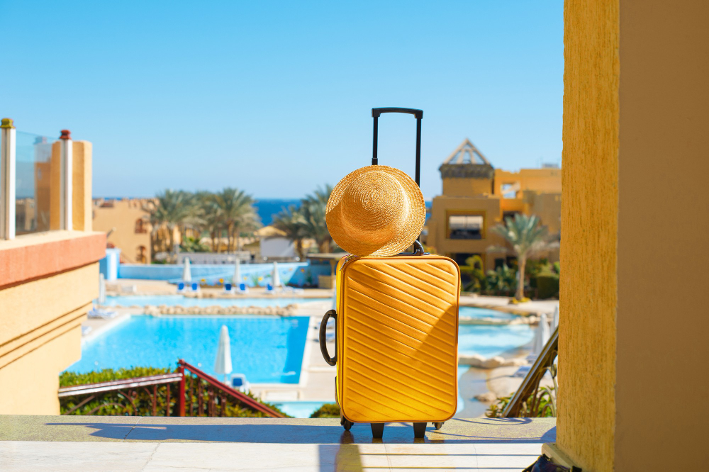 travel-summer-holidays-vacation-concept-yellow-suitcase-with-hat-background-hotel-pool-area-egypt