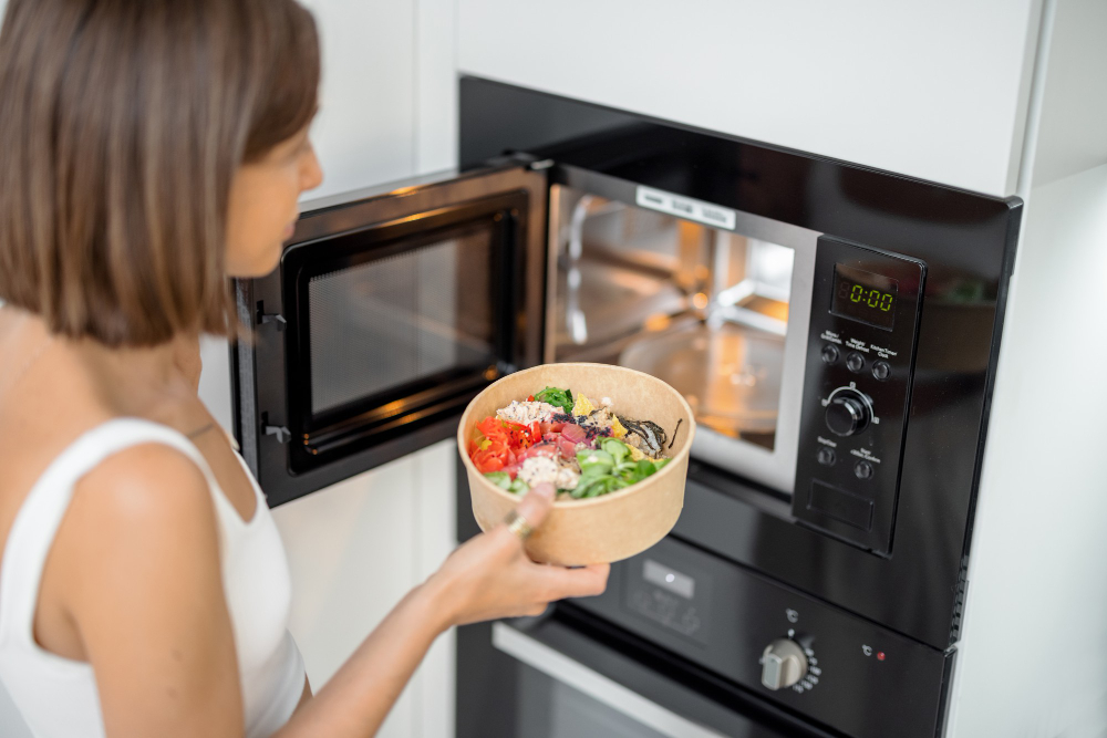 Woman Heating Food With Microwave Machine