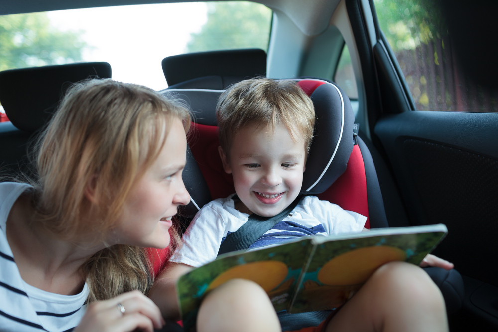 boy-holding-book-sitting-car-with-mother