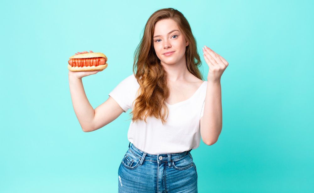 Red Head Pretty Woman Making Capice Money Gesture Telling You Pay Holding Hot Dog